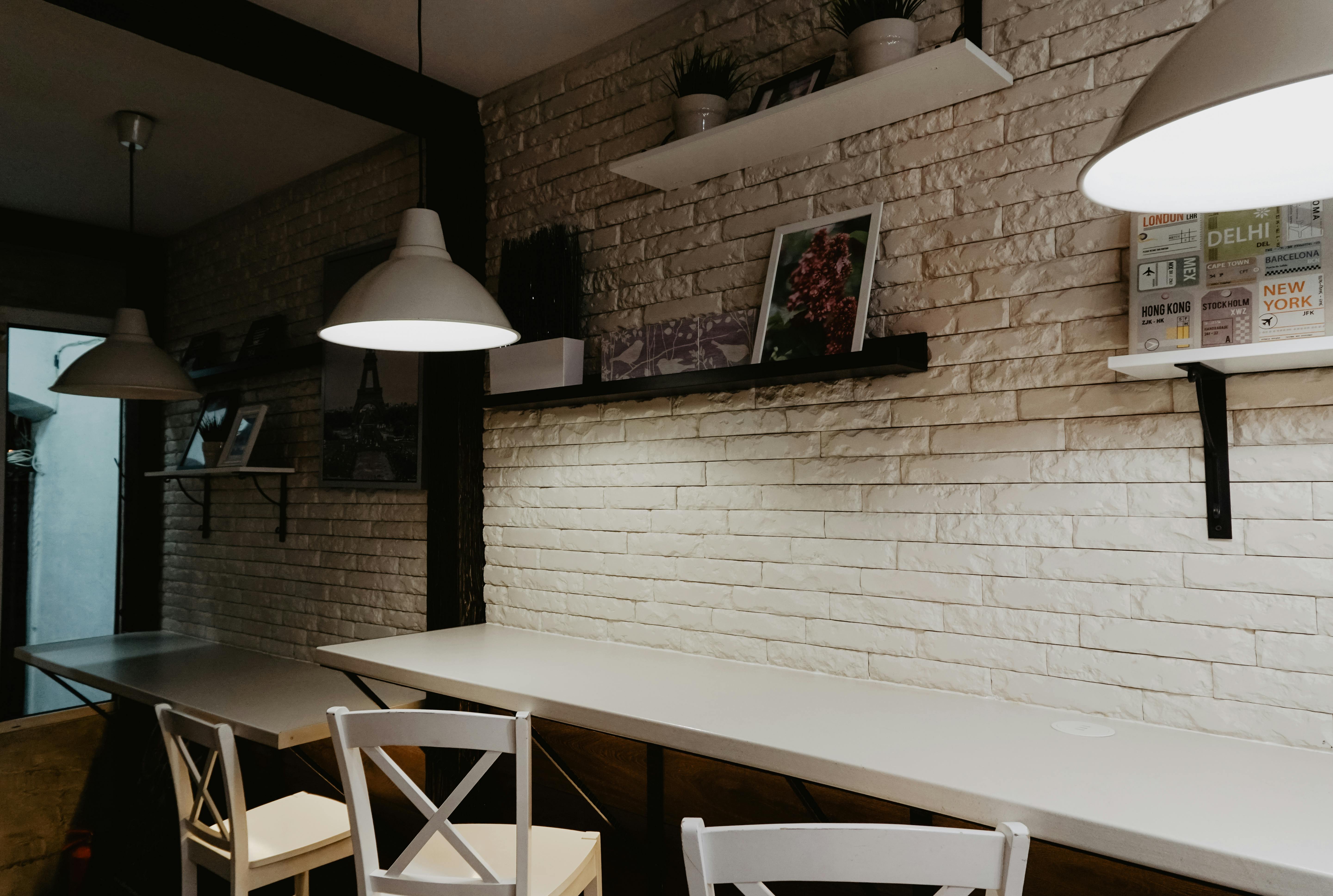Free Cozy cafe interior featuring modern design with hanging lamps and decorative shelves on a brick wall. Stock Photo