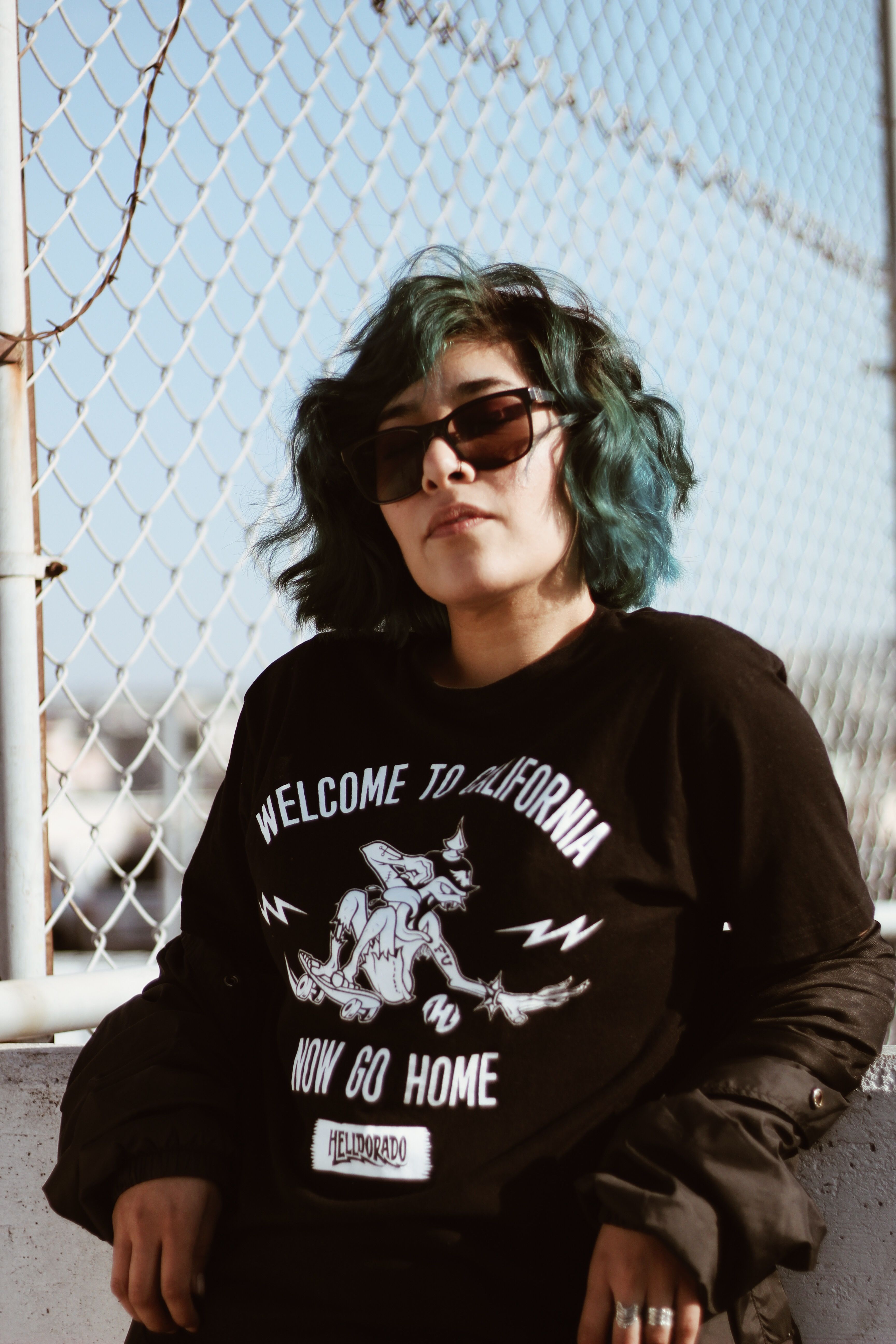 Woman with sunglasses poses stylishly outdoors, wearing a graphic tee.