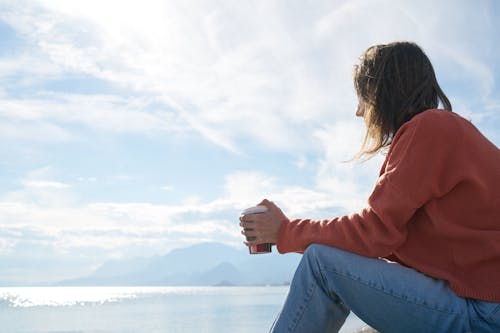 Person, Die Vor Dem Gewässer Sitzt