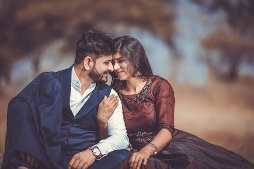 A loving couple sharing a tender moment outdoors, highlighting their romantic connection and stylish attire.