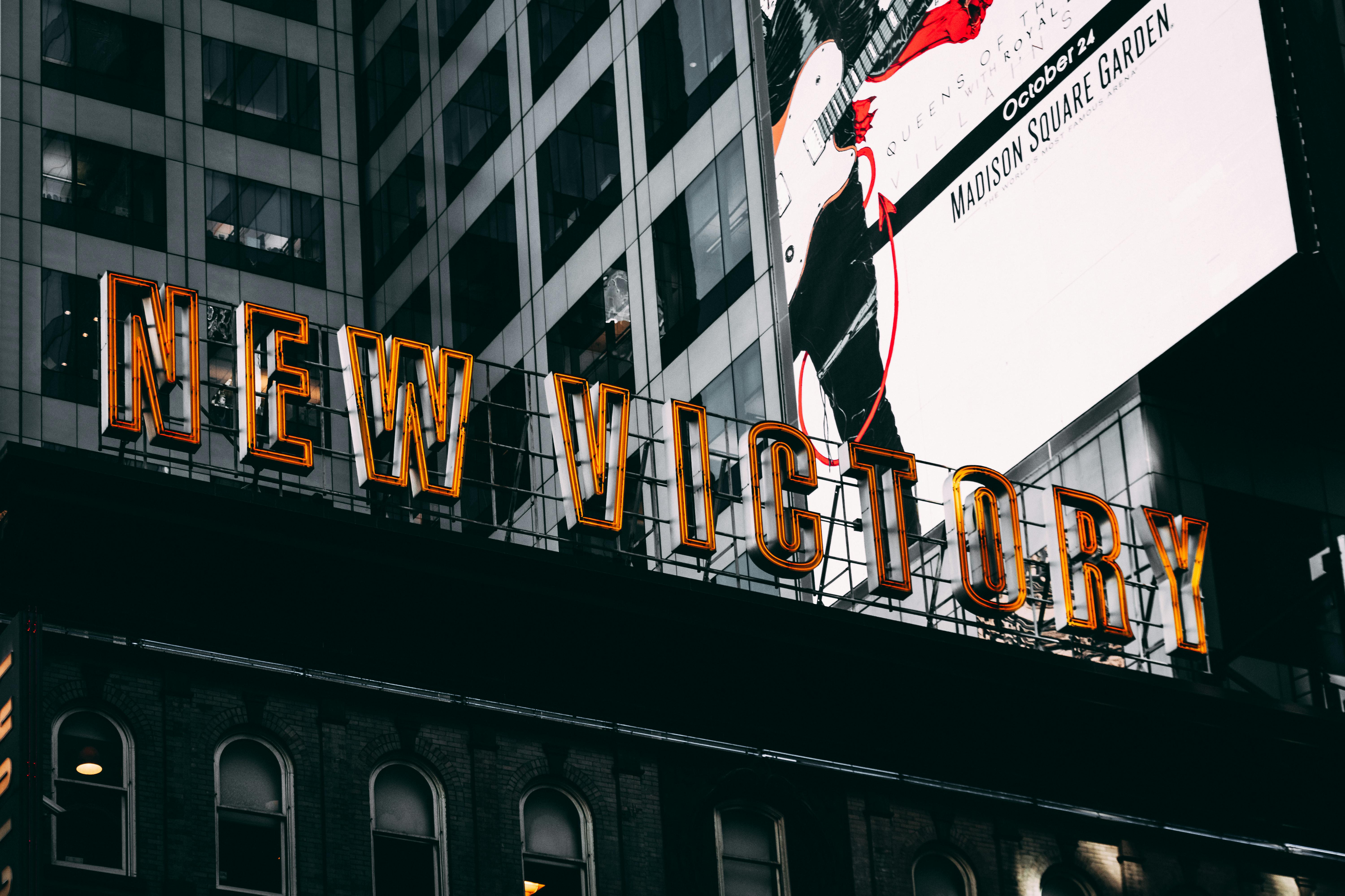 low angle photography of new victory sign below madison square garden billboard