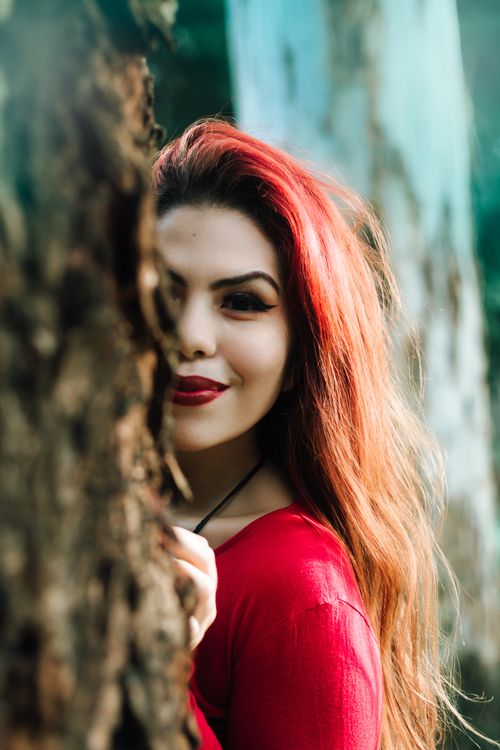 Free Portrait of a red-haired woman with a vibrant smile in a natural outdoor setting. Stock Photo