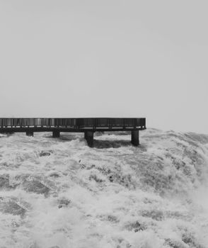 Black and white photo of a dramatic waterfall with a pier in Brazil.