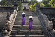 两名身着传统服装的妇女登上石阶，来到一座古庙，感受文化遗产