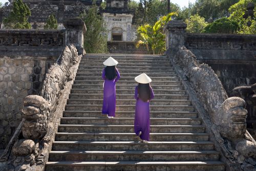 Free Two women in traditional attire ascend stone steps to an ancient temple, capturing cultural heritage. Stock Photo
