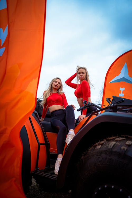 Two women in red and orange sitting on a quad