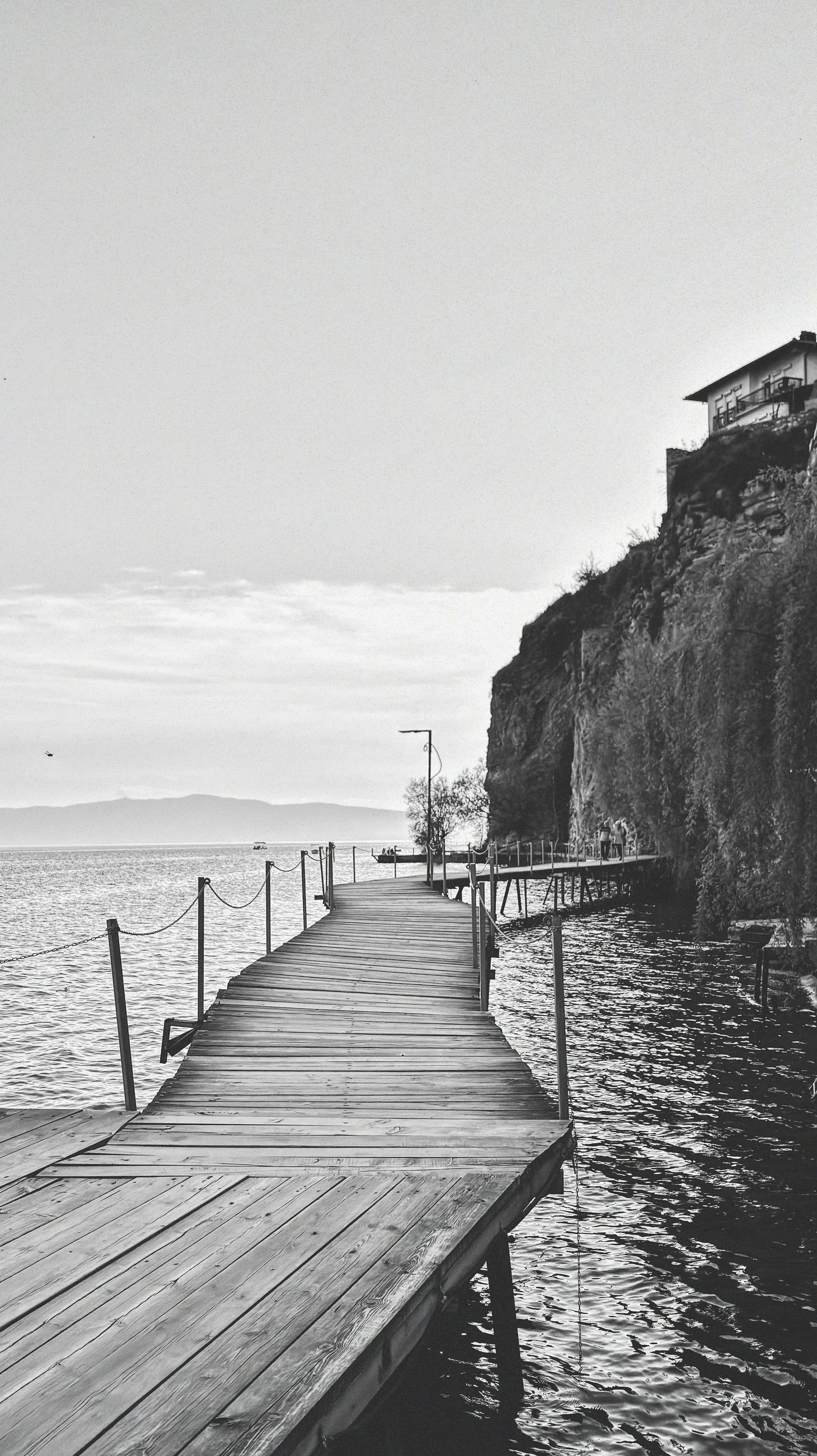 Tranquil black and white shot of a wooden pier over a calm lake in Ohri, North Macedonia.