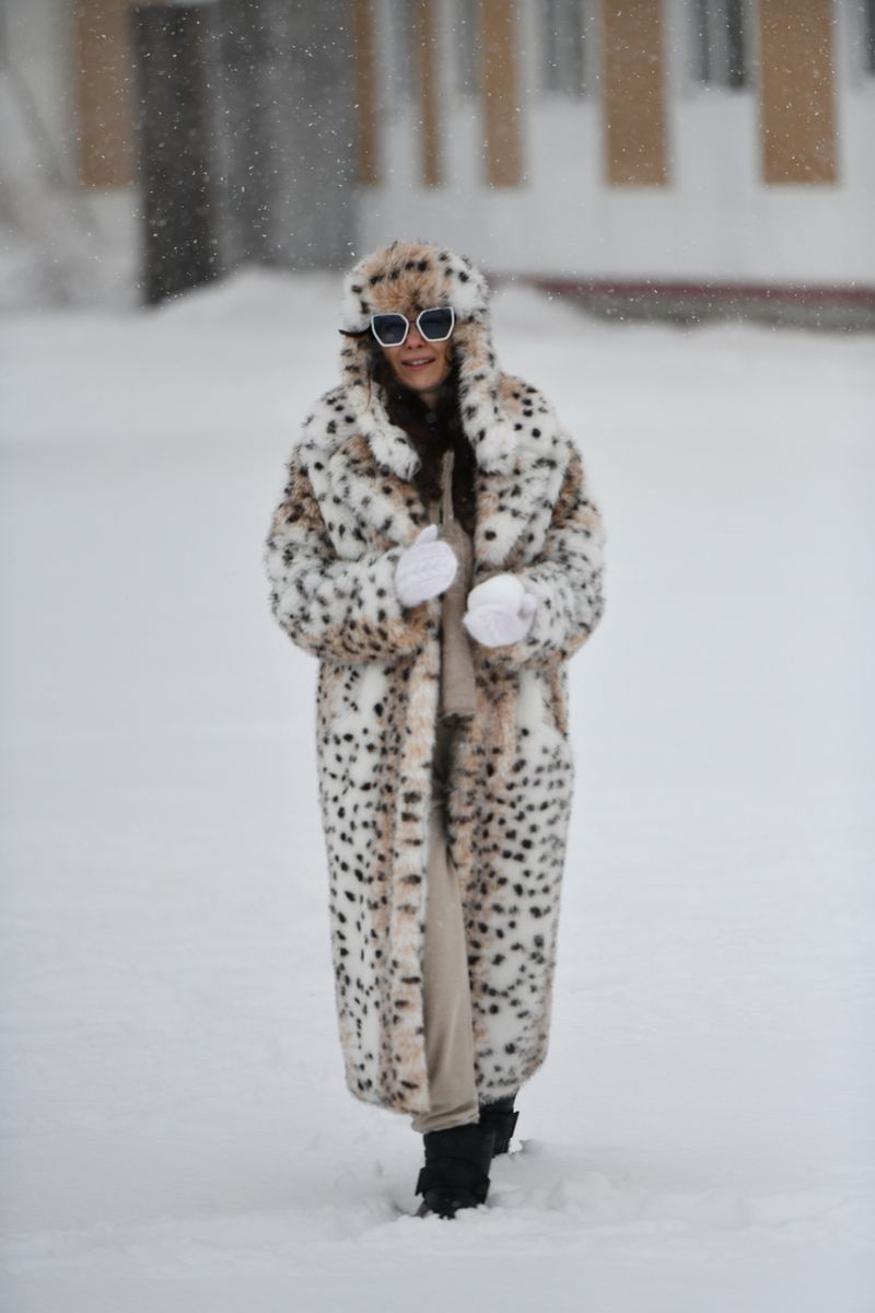 Woman in faux fur coat standing in the snow