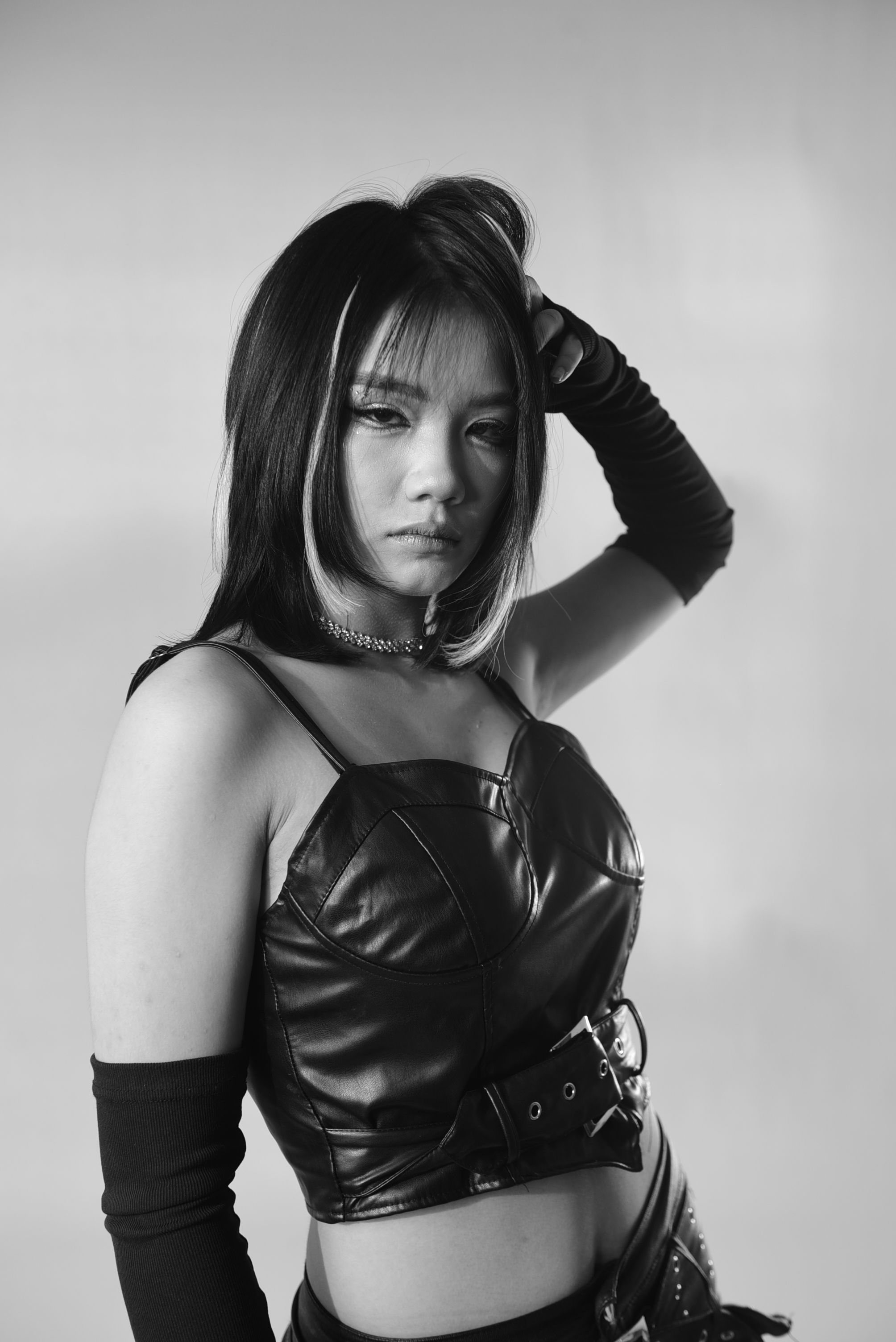 Black-and-white editorial portrait of a model in leather clothing