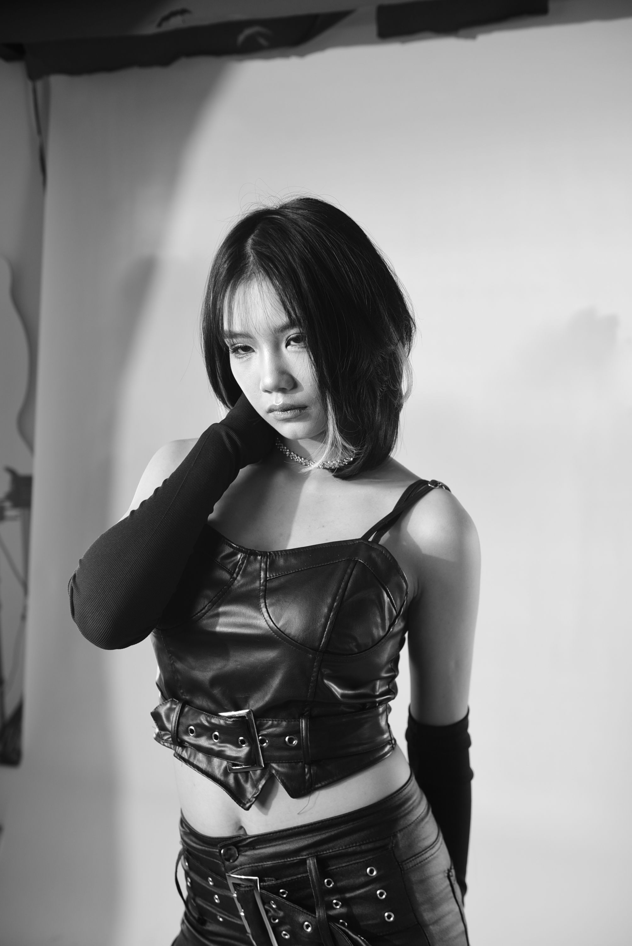 Black and white portrait of an Asian woman in leather fashion, exuding a modern and edgy vibe.