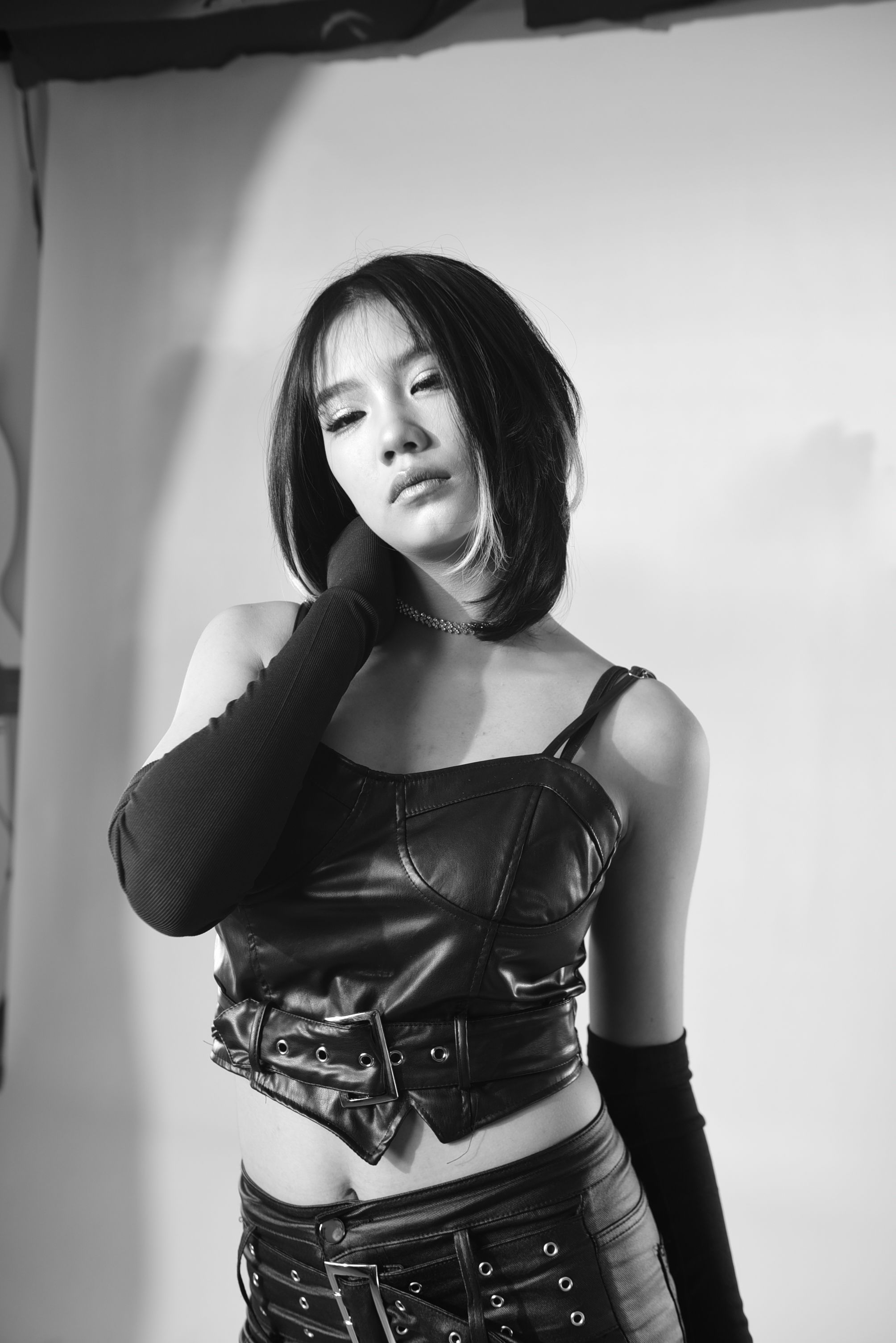 Stylish black and white portrait of an Asian woman in fashionable leather attire.