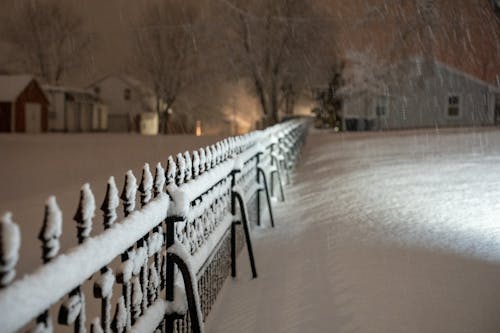 A snow covered fence at night with lights