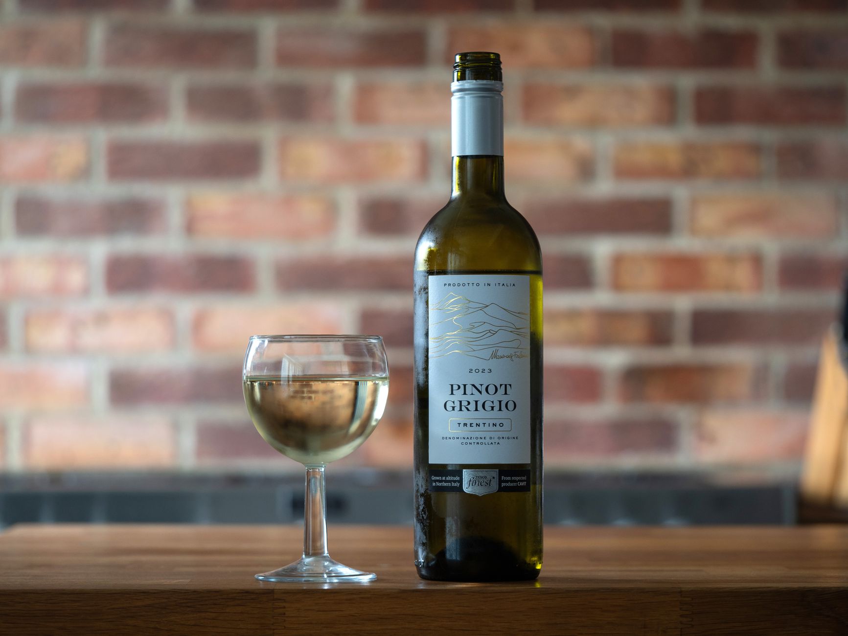 Glass of Pinot Grigio on a rustic wooden table with fresh grapes