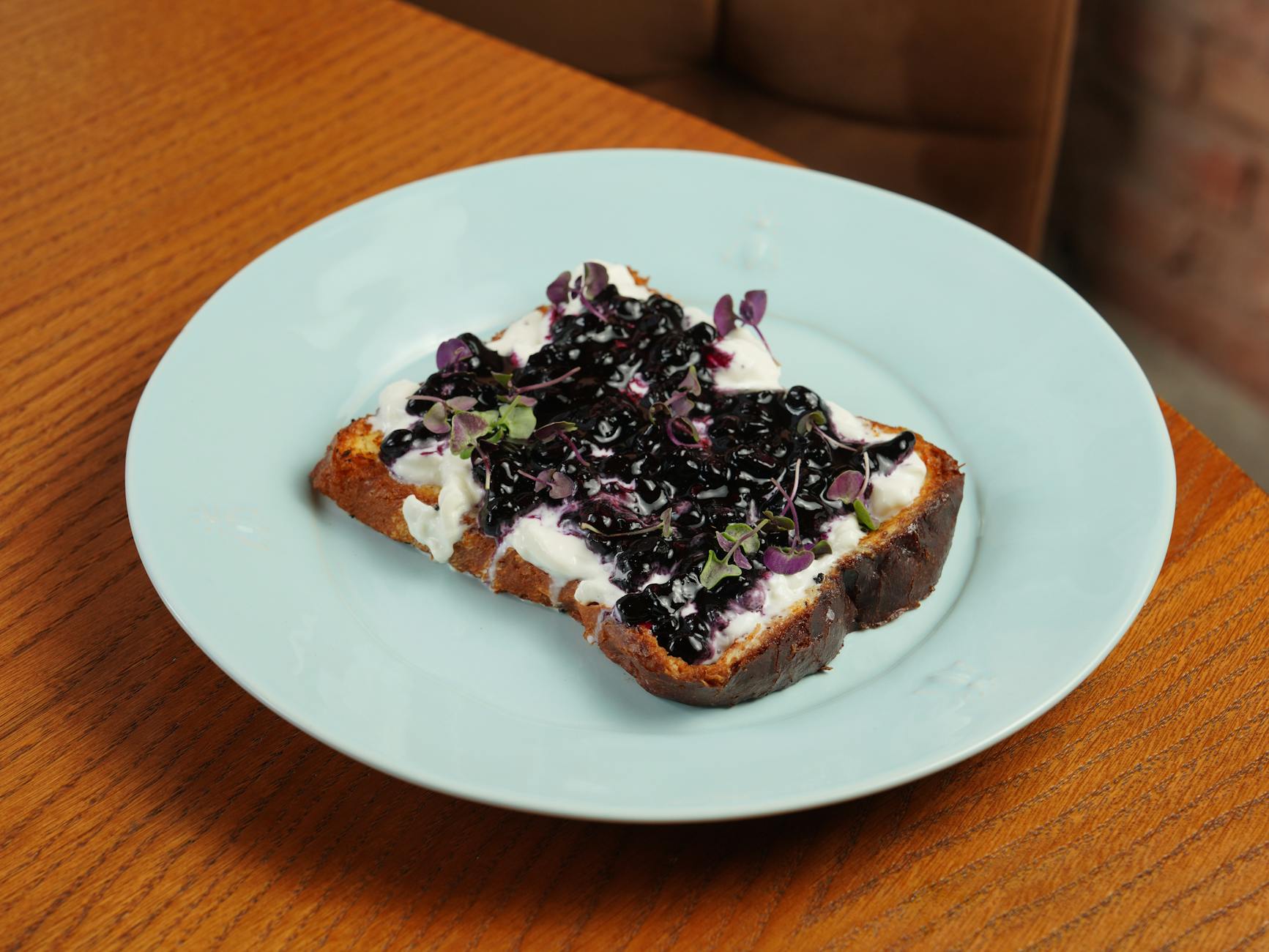 A plate topped with a piece of toast with blueberries and onions