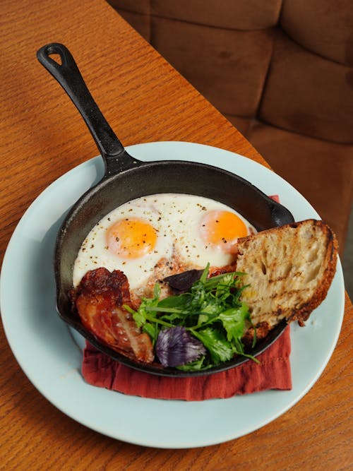 Free Baked Eggs with a Slice of Bacon, Salad and Toasted Bread  Stock Photo