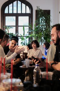 Group of friends enjoying a casual chat in a cozy cafe setting; vibrant and warm atmosphere.