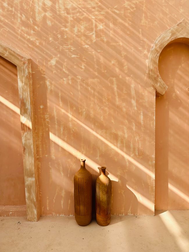 Two amphorae against a sunlit plaster wall — DARKMODE CINEMA on Pexels