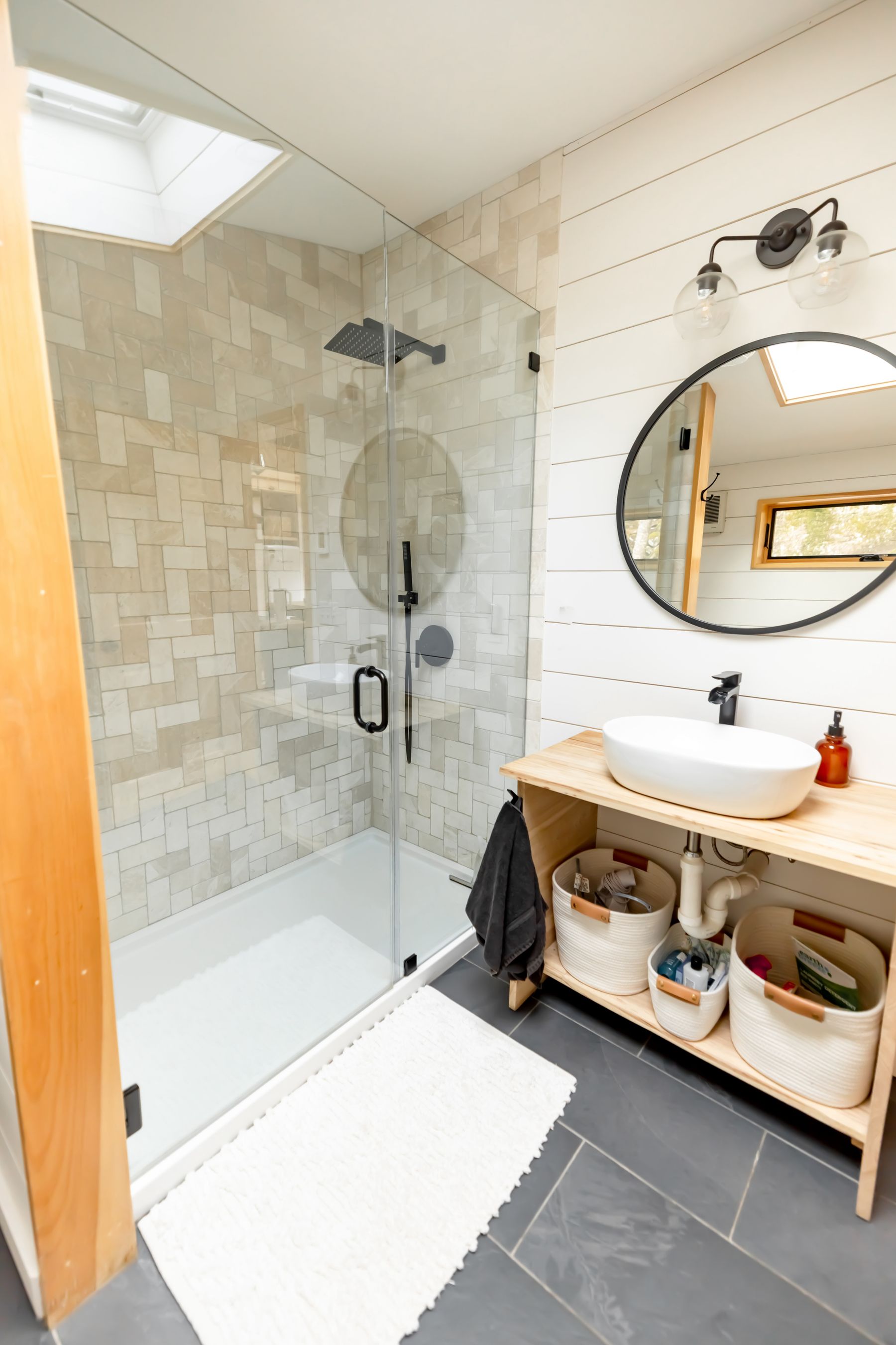 Warm neutral bathroom with a clear glass shower, pale tile and timber accents