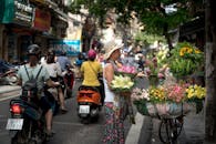 热闹的城市街景中，一家花店正从自行车上出售五颜六色的鲜花