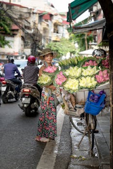 一名身穿花卉连衣裙的女子在繁忙的城市街道上售卖美丽的莲花