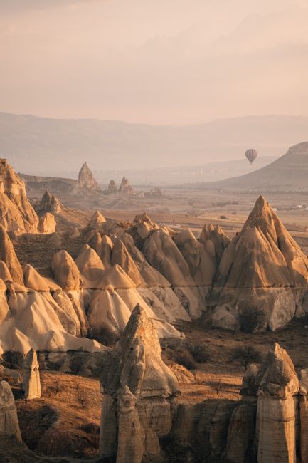 Beautiful rock formations in Cappadocia with a hot air balloon at sunrise, showcasing Göreme's unique geology.