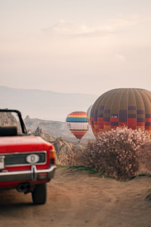 A red car and hot air balloons in the desert