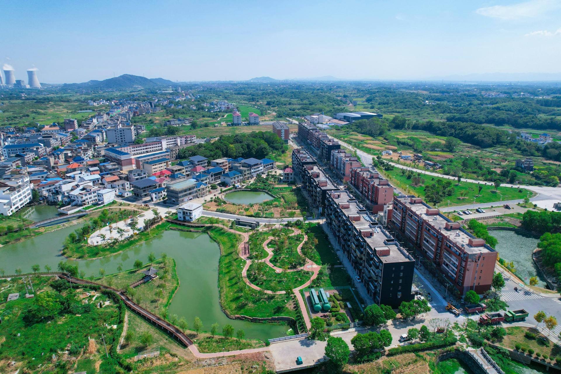 Aerial shot of Jiujiang city showing residential areas, greenery, and water features under a clear sky.