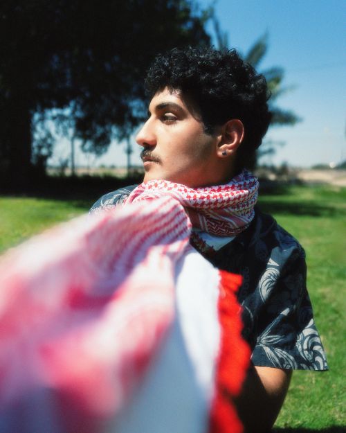 Free Young Middle Eastern man with traditional scarf in a sunny outdoor setting. Stock Photo