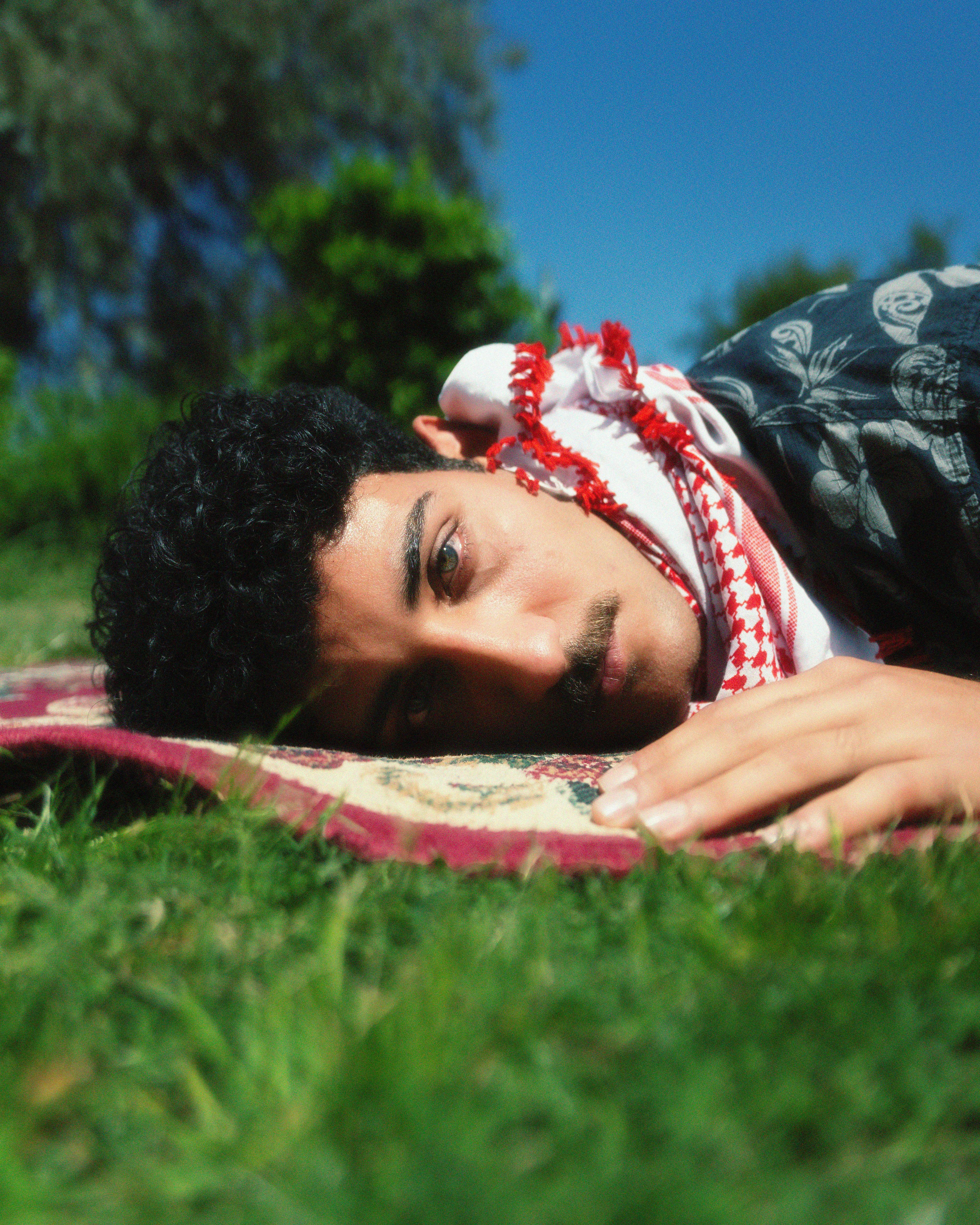 Portrait of a man lying on a rug outside in a rural area, enjoying the day.