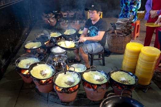 Street food vendor prepares traditional dishes using multiple cooking pots over open flames.