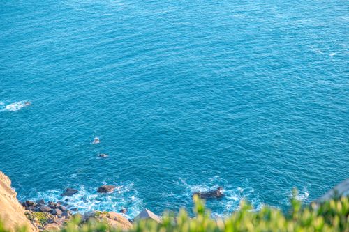 Free Aerial view of a serene coastline with clear blue waters and rocky shore. Stock Photo