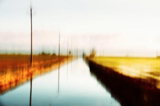 Blurred canal view with vibrant colors creating a serene, abstract landscape.