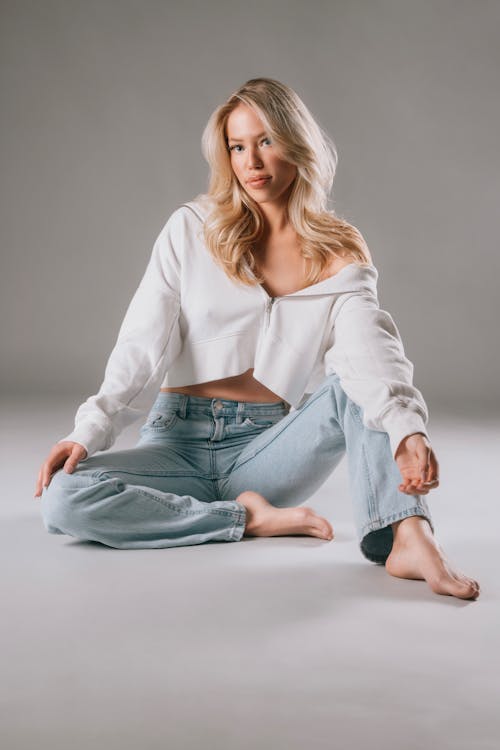 Blonde Woman Sitting on Gray Background