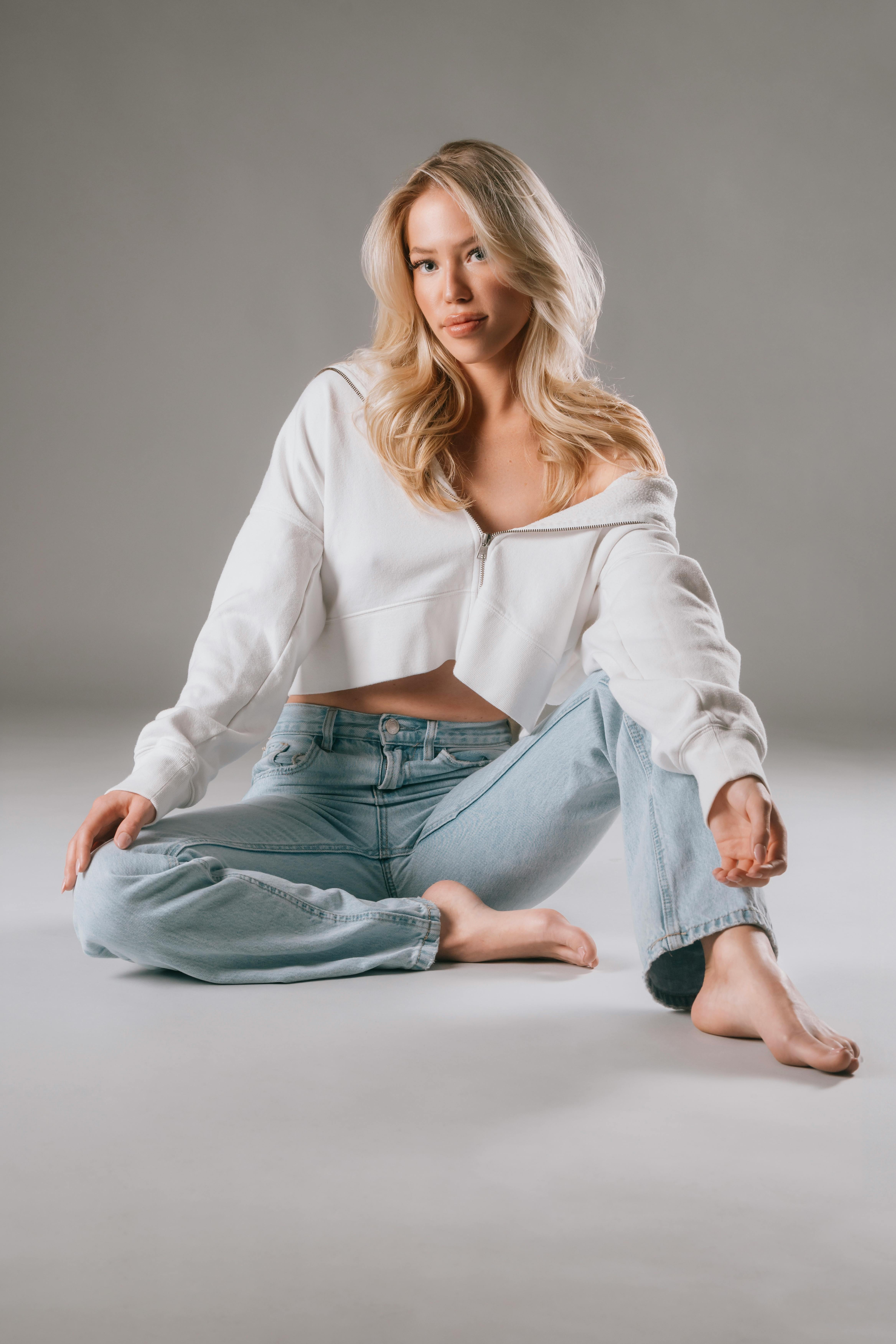 Blonde Woman Sitting on Gray Background · Free Stock Photo