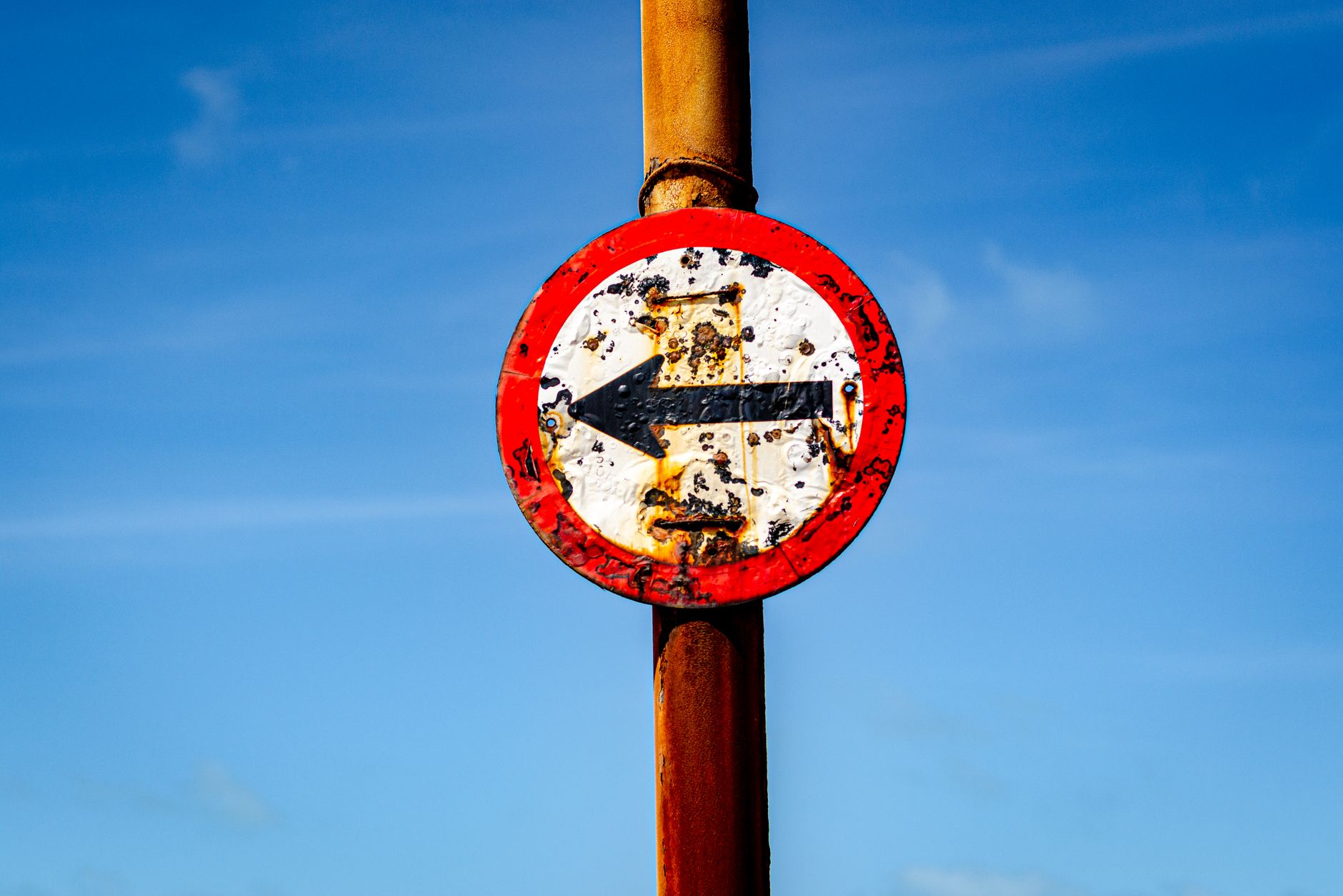 An old rusty no entry sign with clear blue sky background illustrating time and neglect.