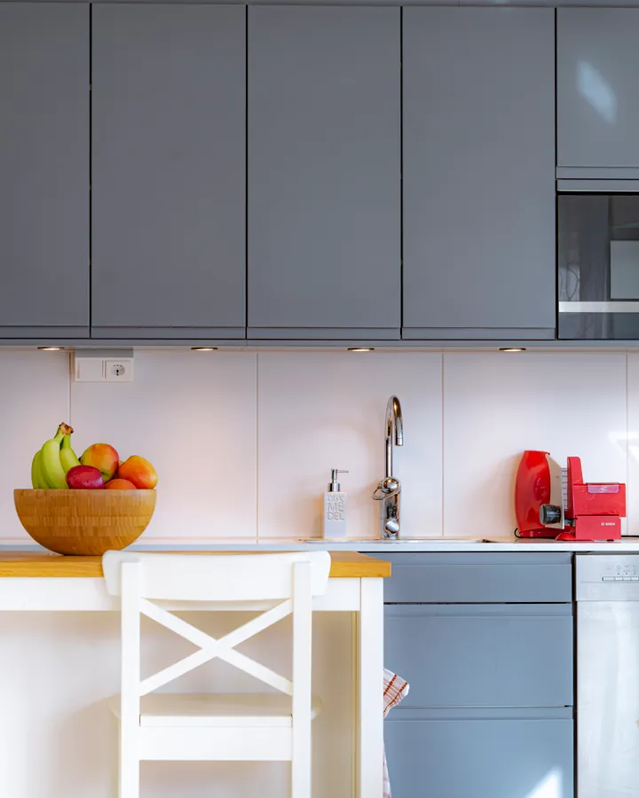 How Often to Change Your Refrigerator Water Filter Modern kitchen with blue cabinets and a bowl of fruit on the countertop