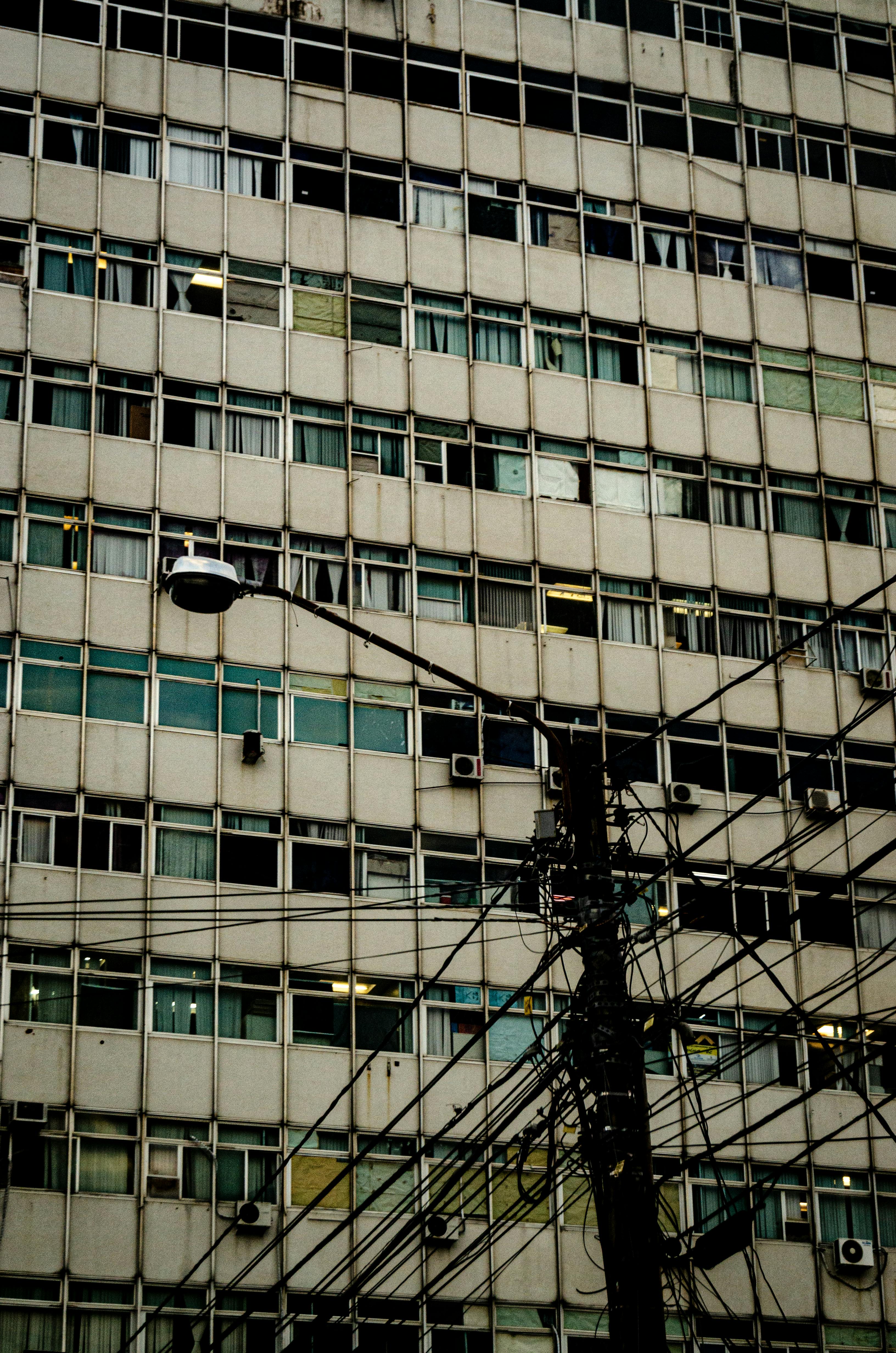 Low angle shot of a building facade with a street lamp and power lines in an urban setting.