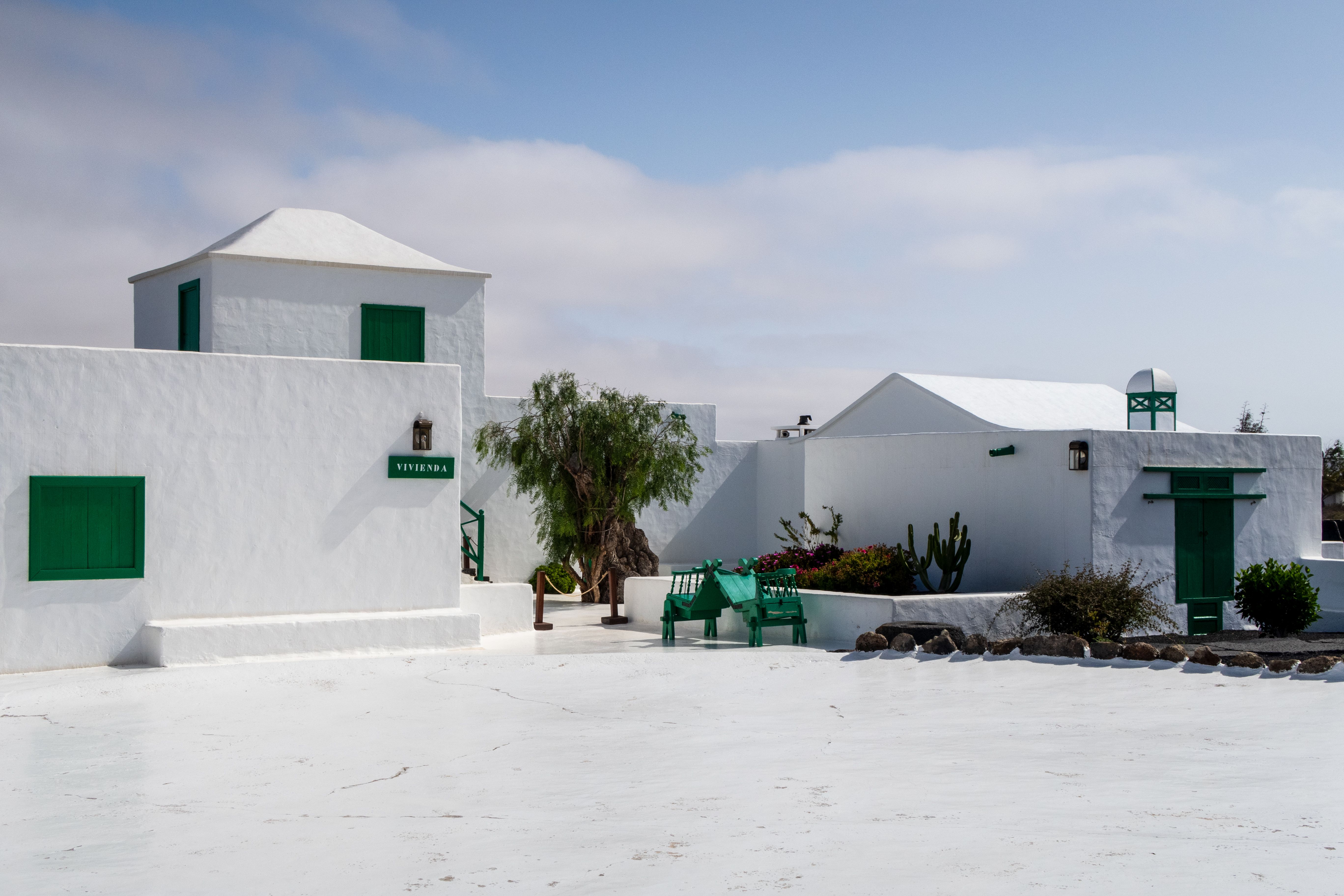Charming white buildings with green accents under a blue sky in Lanzarote, Spain.