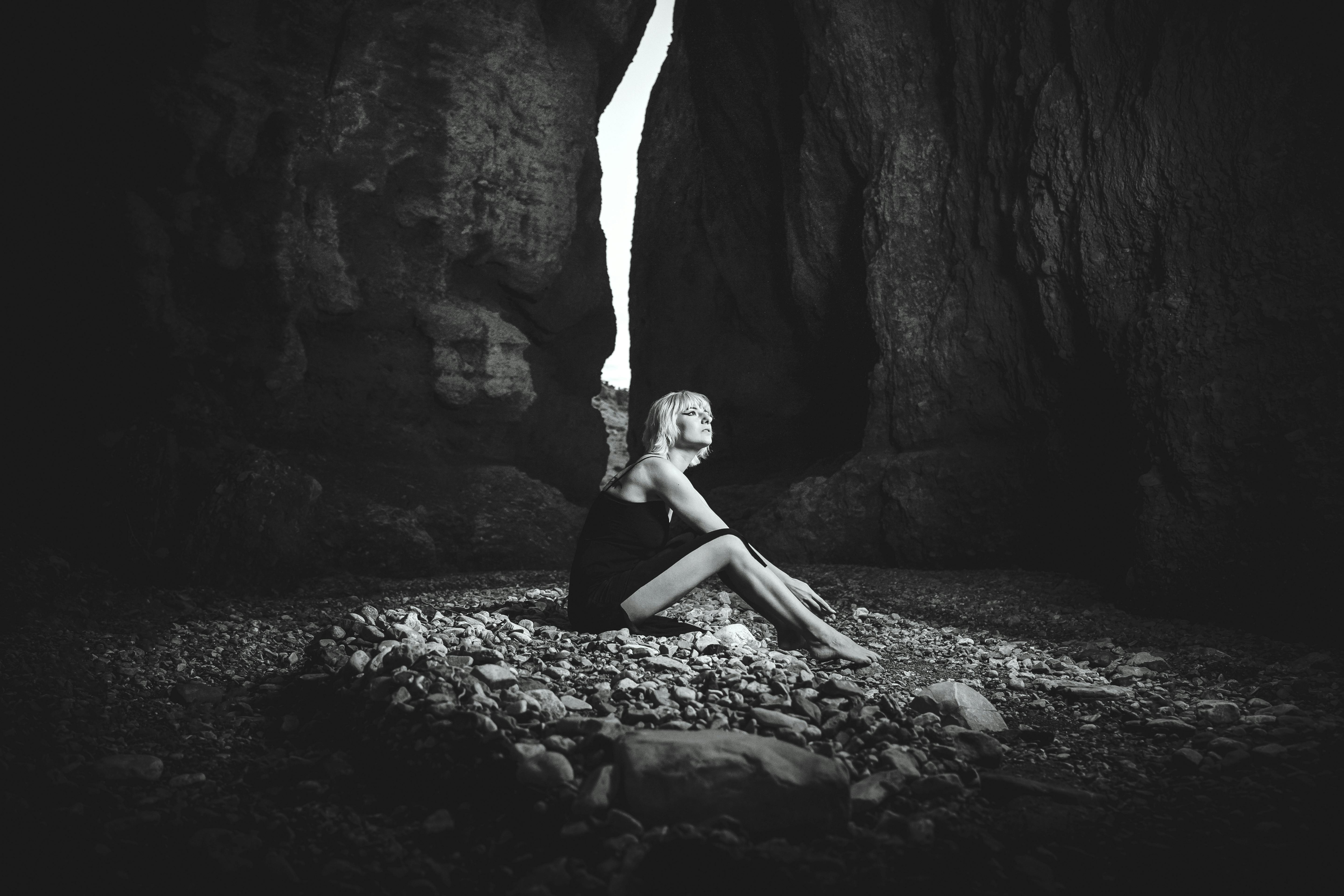 black and white photo of a woman in a dress sitting in a canyon gorge