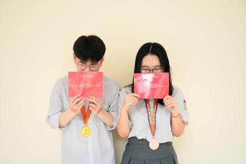 Two people holding up their red envelopes and holding up their phones