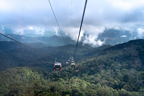 Free A breathtaking view of cable cars traversing over a green mountain landscape with clouds. Stock Photo