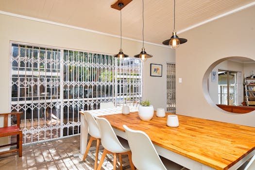 Spacious dining room featuring wooden table and pendant lights, showcasing modern interior design.