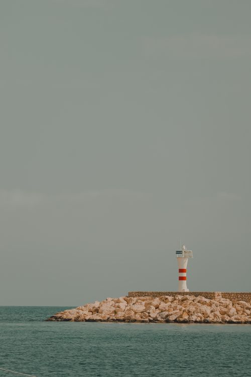 Free Minimalist view of Taşucu lighthouse on rocky coastline under a clear sky. Stock Photo