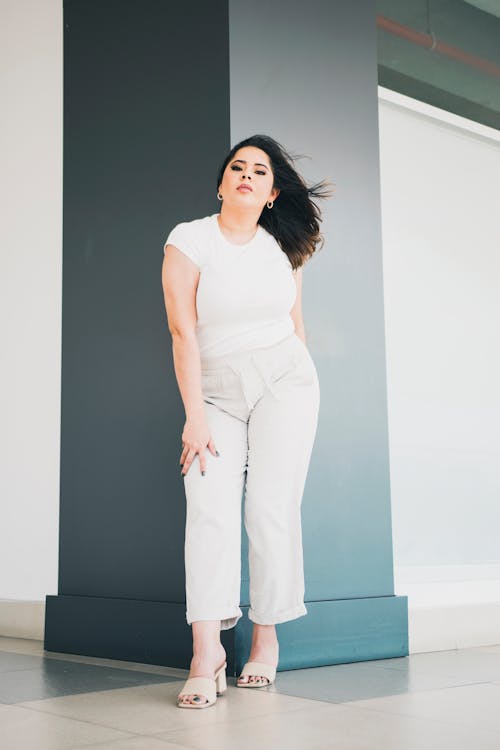 A woman in white pants and heels posing for a photo