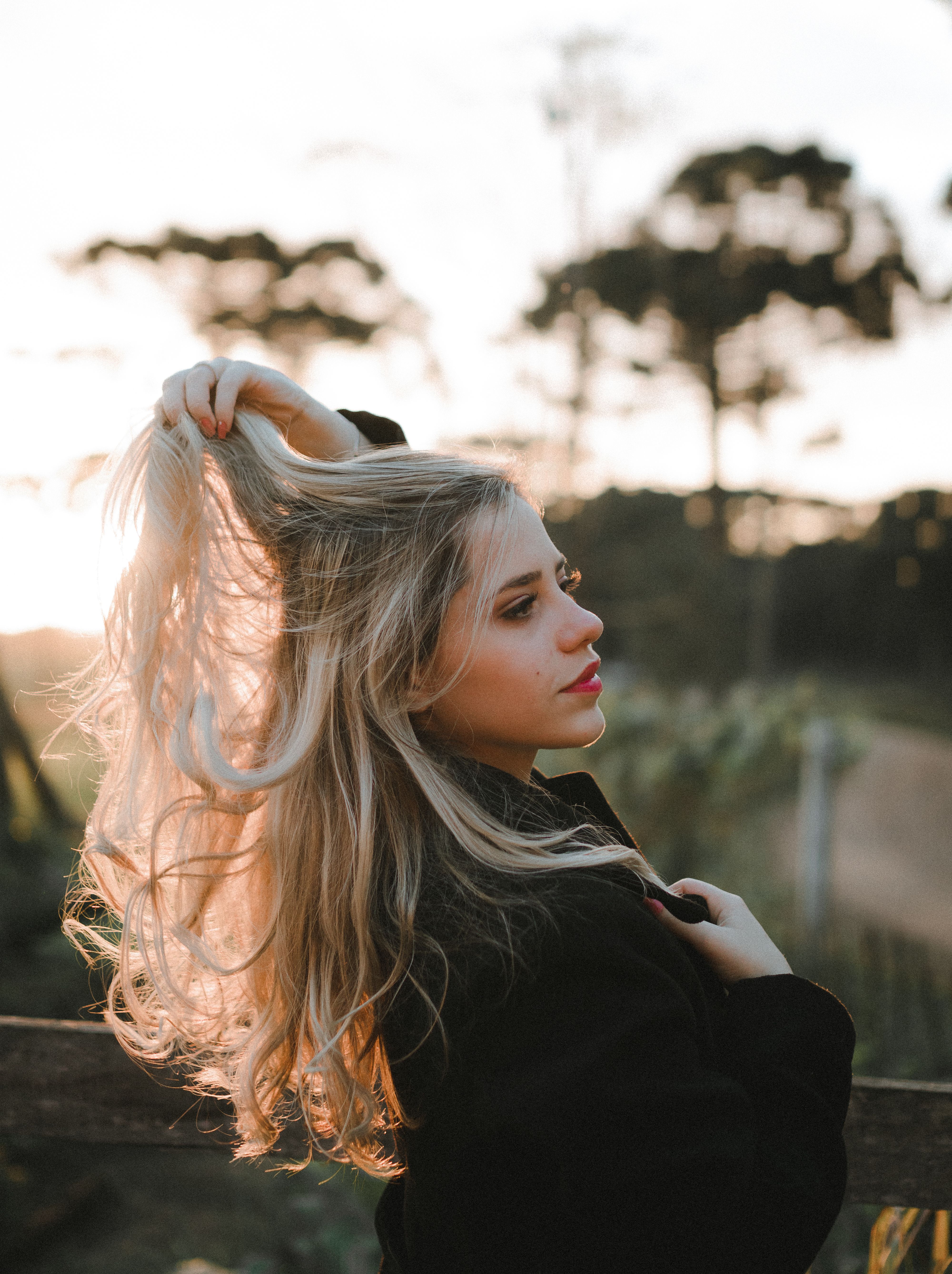 A blonde woman posing in a sunlit field, capturing the essence of golden hour in a serene outdoor setting.