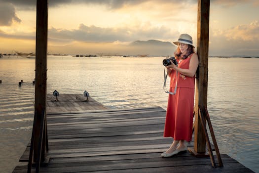日落时分，一位女摄影师站在湖边宁静的码头上，捕捉着眼前的景象