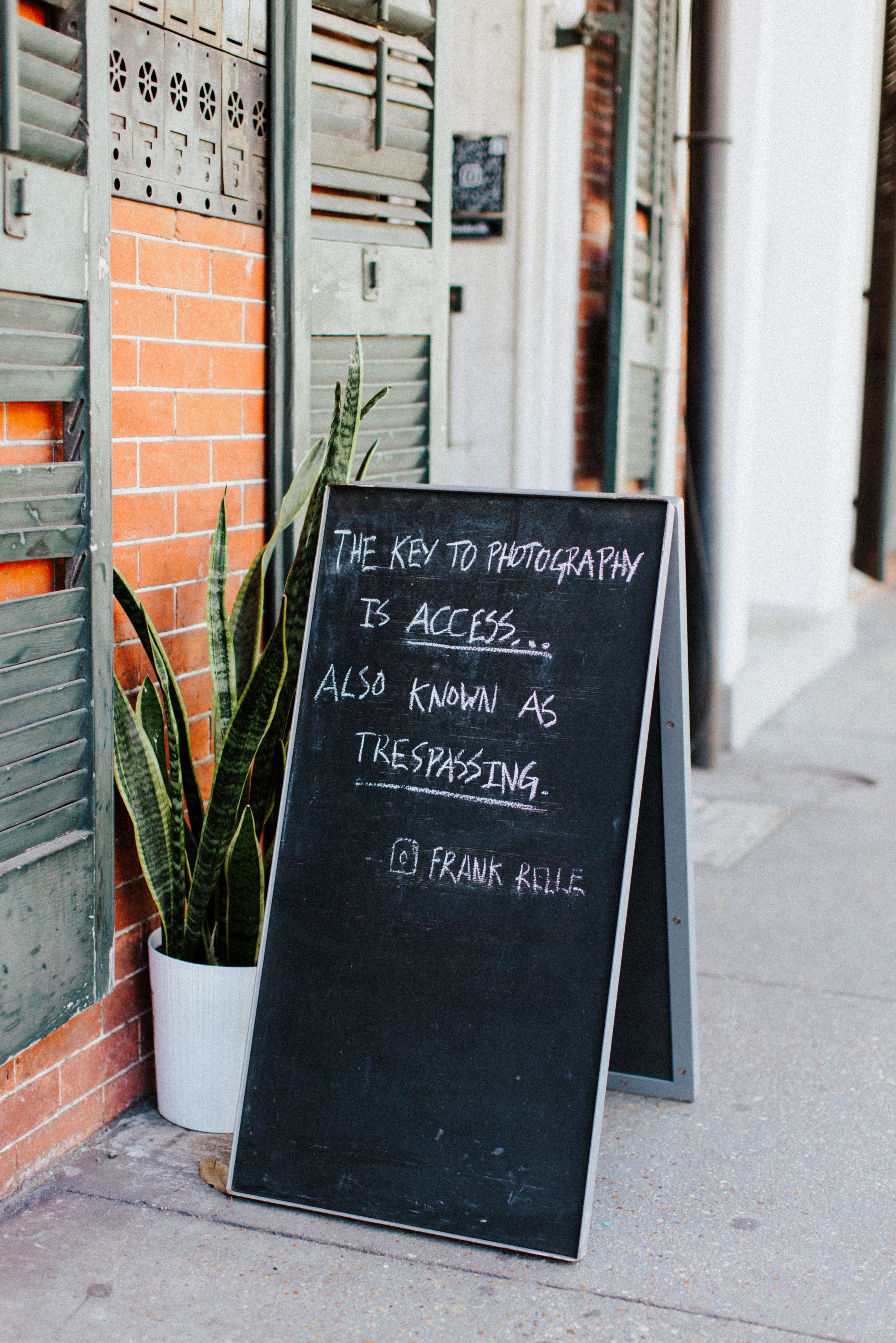 A chalkboard with a humorous quote on photography on a city sidewalk.