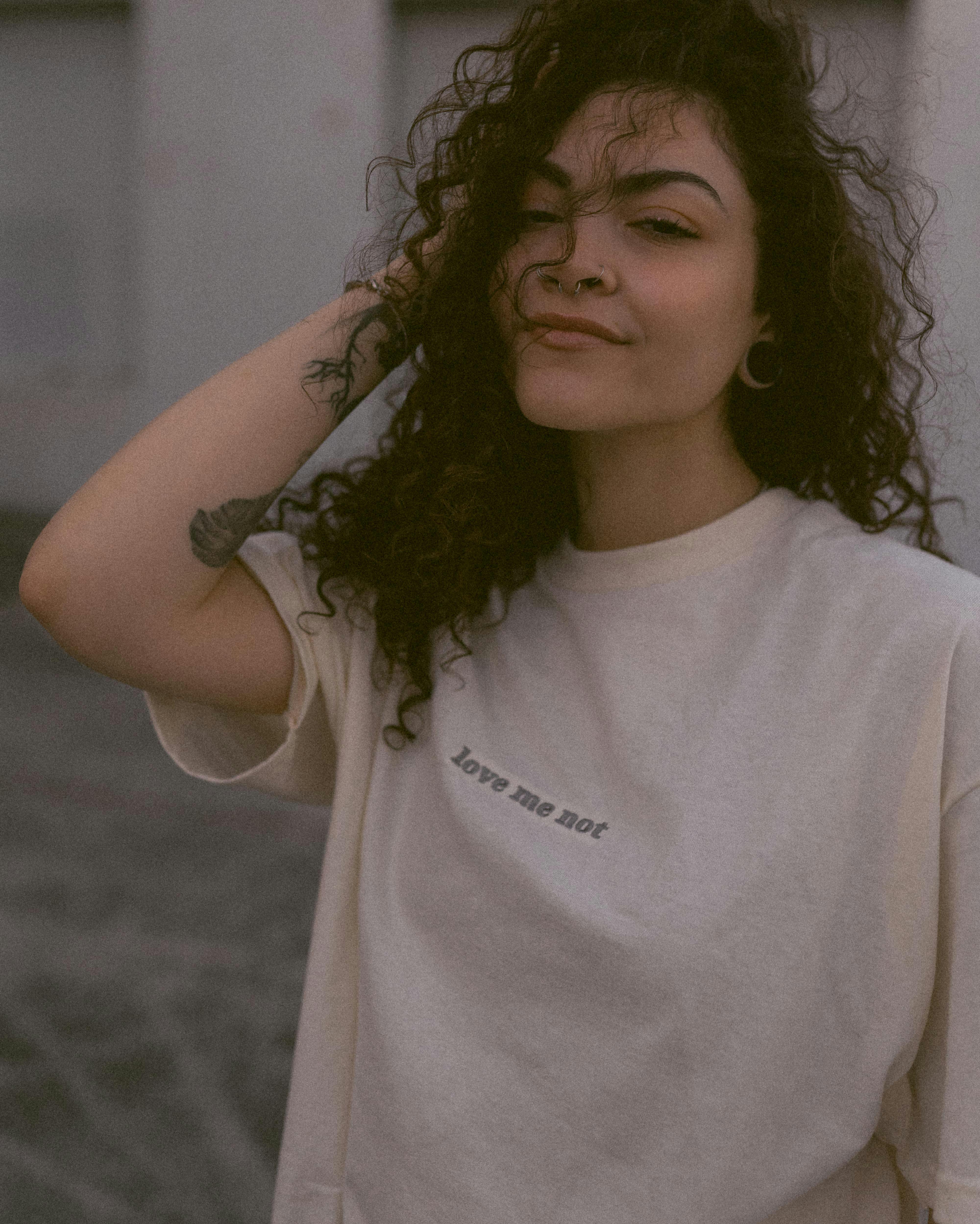 Portrait of a relaxed woman with curly hair wearing a white t-shirt outdoors.