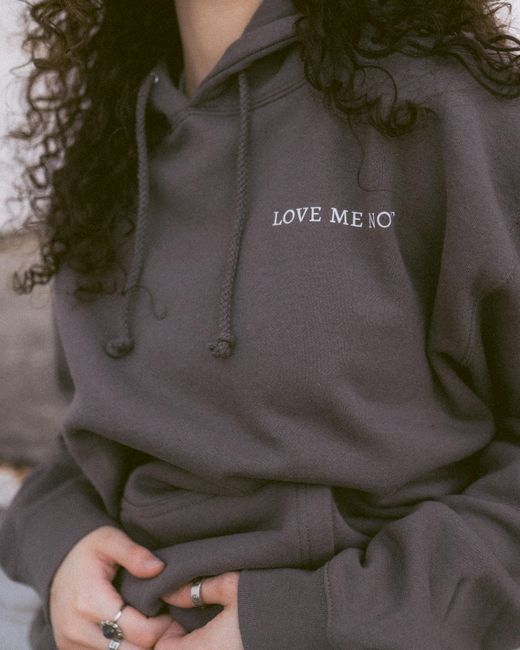 Fashion photo of a woman in a gray hoodie with curly hair and rings, conveying relaxed style.