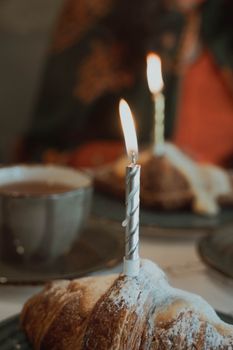 Warm ambiance of a café with burning candles on croissants, perfect for birthdays.